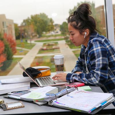 Student studying in front of windows overlooking campus from University View